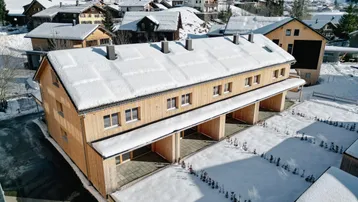 Luftaufnahme der neuen Reihenhäuser mit Holzfassade, umgeben von verschneiter Landschaft.