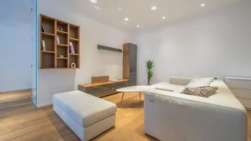Modernes Wohnzimmer mit hellem Sofa, Holzboden und integrierten Deckenleuchten.