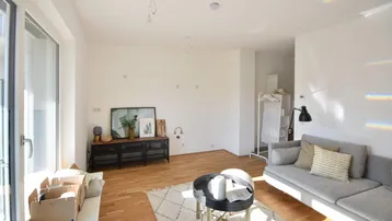 Helles Wohnzimmer mit Holzboden, großem Fenster und moderner Einrichtung, bereit zum Einzug.