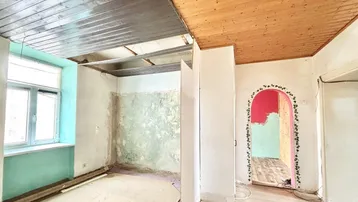 Unfertiger Innenraum mit Holzbalkendecke und Renovierungsbedarf, bereit für die Neugestaltung.