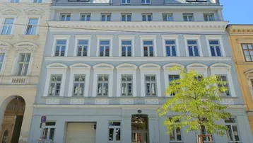 Die moderne Fassade des Gebäudes mit vielen Fenstern und einem Mansarddach.