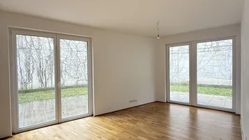 Helles Wohnzimmer mit Parkettboden und großen Fenstern, die Zugang zur Terrasse bieten.