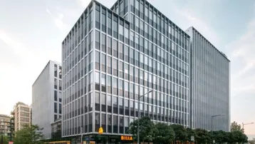 Modernes Bürogebäude mit Glasfassade und Einzelhandelsflächen im Erdgeschoss an einer belebten Straße.
