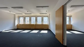 Leerer Büroraum mit Teppichboden, großen Fenstern und viel Tageslicht, ideal für flexible Arbeitsplatzgestaltung.
