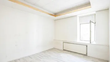 Helles, leeres Zimmer mit Laminatboden und einem Fenster, bereit zur individuellen Gestaltung.
