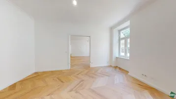 Helles Zimmer mit Fischgrätparkett und weißen Wänden, bereit zur individuellen Gestaltung.