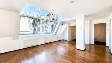 Helles Wohnzimmer mit großen Dachfenstern, Holzboden und weitem Blick über die Stadt.