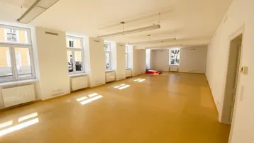 Großer, heller Büroraum mit vielen Fenstern und gelbem Linoleumboden, ideal für gewerbliche Nutzung.