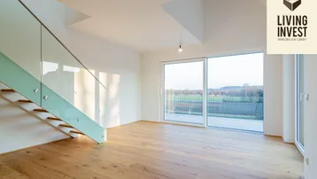 Helles Wohnzimmer mit Holzparkett, moderner Glastreppe und Zugang zu einer Terrasse mit Weitblick.