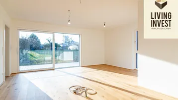 Helles Wohnzimmer mit Holzboden, großen Schiebetüren und Zugang zum Gartenbereich.