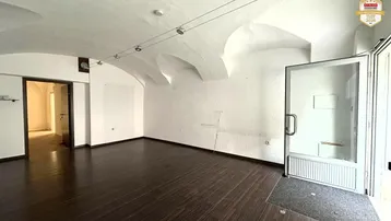 Geräumiger Innenraum mit dunklem Holzboden, weißen Wänden und einer markanten Gewölbedecke, ideal für Gewerbezwecke.