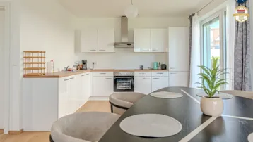 Moderne Küche mit weißen Schränken, Holzarbeitsplatte und Essbereich mit Zugang zur Terrasse.