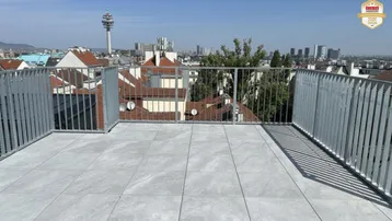 Große Dachterrasse mit Fliesenboden und weitem Blick über die Stadt und den Donauturm.