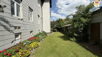 Gepflegter Gartenbereich mit Rasenfläche, bunten Blumenbeeten und seitlichem Blick auf das Gebäude.
