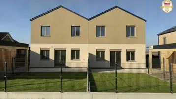 Ansicht der modernen Doppelhaushälfte mit beiger Fassade und kleinem Vorgarten.