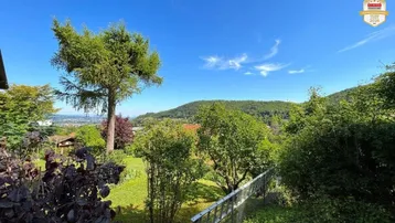 Grüner Gartenbereich mit Bäumen und weitem Blick über die Landschaft und Hügel.