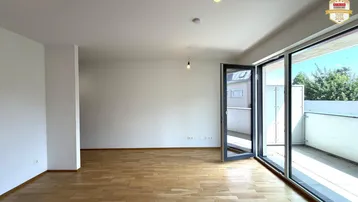 Helles Wohnzimmer mit Parkettboden und Zugang zu einem sonnigen Balkon, ideal für entspannte Stunden.