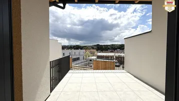 Weitläufiger Balkon mit Fliesenboden und weitem Blick über die Dächer der Umgebung.