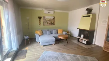 Gemütliches Wohnzimmer mit Kamin, bequemer Couch und Zugang zur Terrasse, hell und einladend.