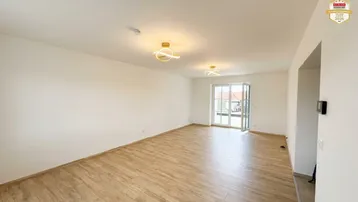 Helles, leeres Wohnzimmer mit modernem Holzboden und Zugang zu einem Außenbereich.