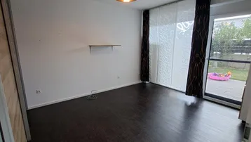 Heller Raum mit dunklem Laminatboden und Zugang zu einem kleinen Gartenbereich.