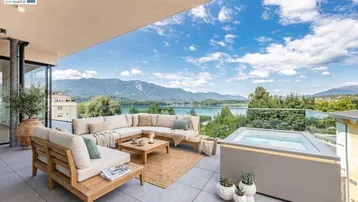 Große möblierte Terrasse mit Whirlpool und atemberaubendem Blick auf den See und die Berge.