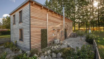 Modernes Holzhaus mit schlichter Fassade und umgebender Natur in ländlicher Lage.
