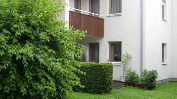 Ansicht eines modernen Mehrfamilienhauses mit Balkonen und gepflegtem Vorgarten.