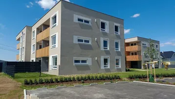 Moderne Wohngebäude mit Balkonen und gepflegter Außenanlage unter blauem Himmel.