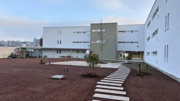 Außenansicht eines modernen Wohnkomplexes mit neu angelegtem Gartenbereich und Gehwegen.