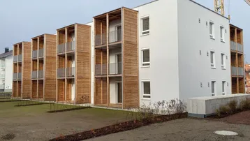 Modernes Mehrfamilienhaus mit Holzverkleidung und Balkonen im Bau.