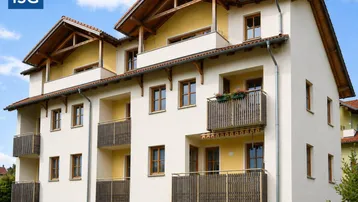 Modernes Mehrfamilienhaus mit heller Fassade, Holzfenstern, Satteldach und mehreren Balkonen mit Holzelementen.