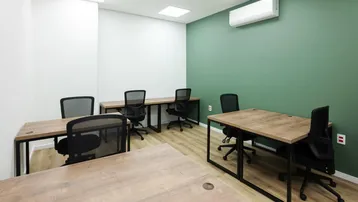 Modernes Büro mit grüner Akzentwand, Holztischen und ergonomischen Bürostühlen, ideal für konzentriertes Arbeiten.