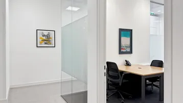 Modernes Büro mit Glastrennwand und Schreibtisch, ideal für konzentriertes Arbeiten in heller Umgebung.
