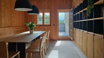 Modernes Esszimmer mit Holzwänden, Holzboden und Zugang zu einem Balkon mit Bergblick.