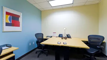 Büro mit zwei Arbeitsplätzen, blauer Akzentwand und Teppichboden, ideal für kleine Teams.