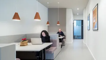 Modernes Büro mit Arbeitsnischen, Pendelleuchten und minimalistischer Einrichtung für konzentriertes Arbeiten.