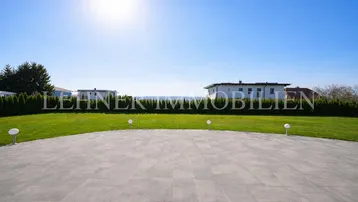 Große gepflasterte Terrasse mit weitem Blick über die grüne Landschaft.