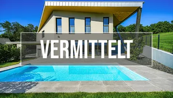 Modernes Haus mit Pool und Garten, umgeben von grüner Landschaft unter blauem Himmel.