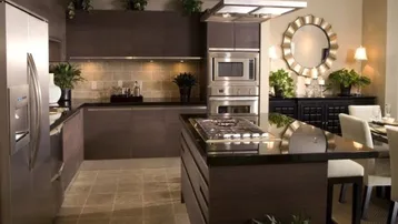 Moderne Küche mit dunklen Holzfronten, Kücheninsel und integrierten Edelstahlgeräten, ideal für Kochliebhaber.