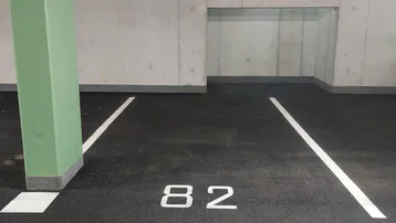 Tiefgaragenstellplatz mit Nummer 82, umgeben von Betonwänden und einem grünen Pfeiler.