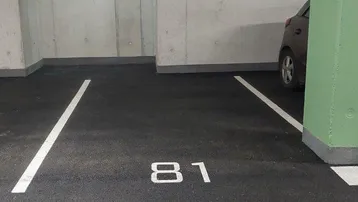 Tiefgaragenstellplatz Nummer 81 mit Betonwänden und -decke in einem gut gepflegten Zustand.