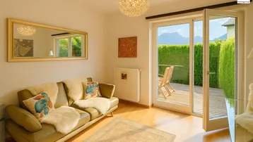 Helles Wohnzimmer mit beiger Couch, Holzboden und Zugang zu einer Holzterrasse mit Bergblick.