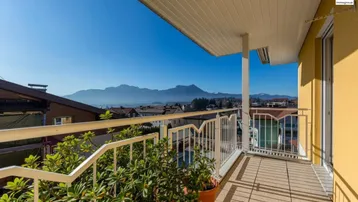 Geräumiger Balkon mit Fliesenboden, Pflanzen und weitem Blick auf die umliegende Berglandschaft.