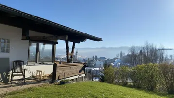 Terrasse mit Rasenfläche und weitem Blick über die Stadt und die umliegenden Berge.