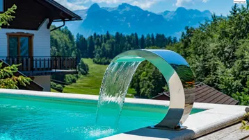 Pool mit modernem Wasserspiel und atemberaubendem Blick auf die umliegende Berglandschaft.