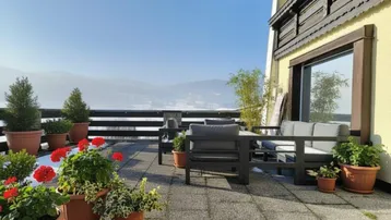 Große Terrasse mit Sitzgelegenheiten und Pflanzen, bietet einen weiten Blick auf die verschneite Berglandschaft.