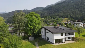 Freistehendes Einfamilienhaus mit Photovoltaikanlage und Blick auf die umliegende Berglandschaft.