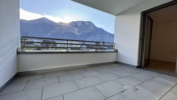 Geräumiger Balkon mit Fliesenboden und beeindruckendem Bergblick unter blauem Himmel.