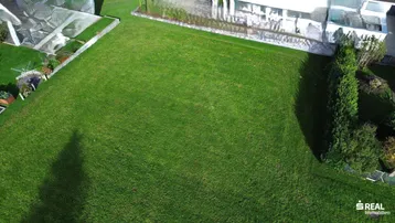 Luftaufnahme eines großen, gepflegten Rasengrundstücks mit umliegenden Gebäuden und viel Grün.